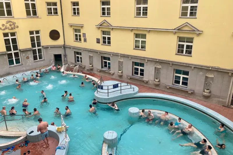Bassins extérieurs des bains Lukács, entourés des façades jaunes du complexe thermal à Budapest.