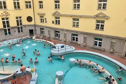 Bassins extérieurs des bains Lukács, entourés des façades jaunes du complexe thermal à Budapest.
