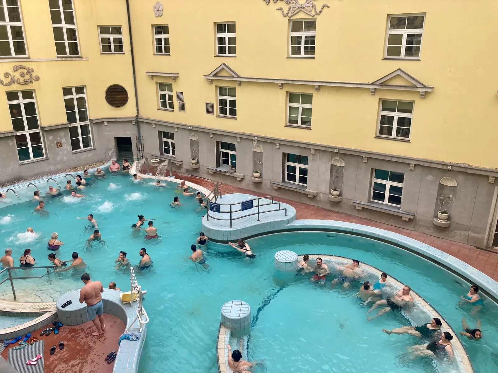 Bassins extérieurs des bains Lukács, entourés des façades jaunes du complexe thermal à Budapest.