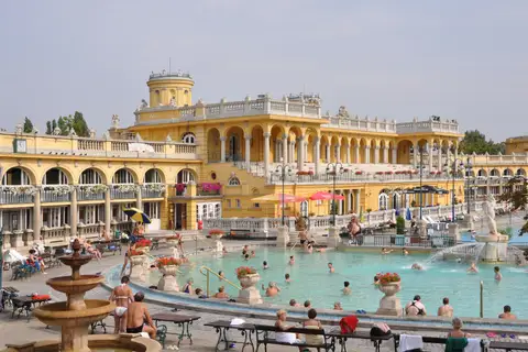 Baigneurs dans le bassin thermal extérieur des bains Széchenyi, devant la façade néo-baroque ocre jaune et sa colonnade, à Budapest.
