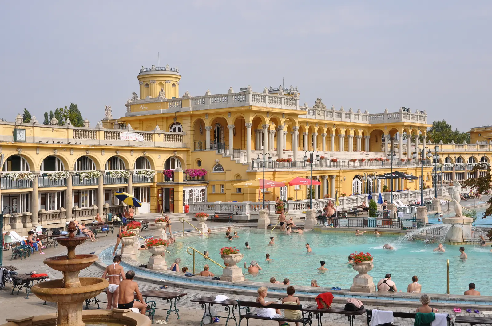Baigneurs dans le bassin thermal extérieur des bains Széchenyi, devant la façade néo-baroque ocre jaune et sa colonnade, à Budapest.