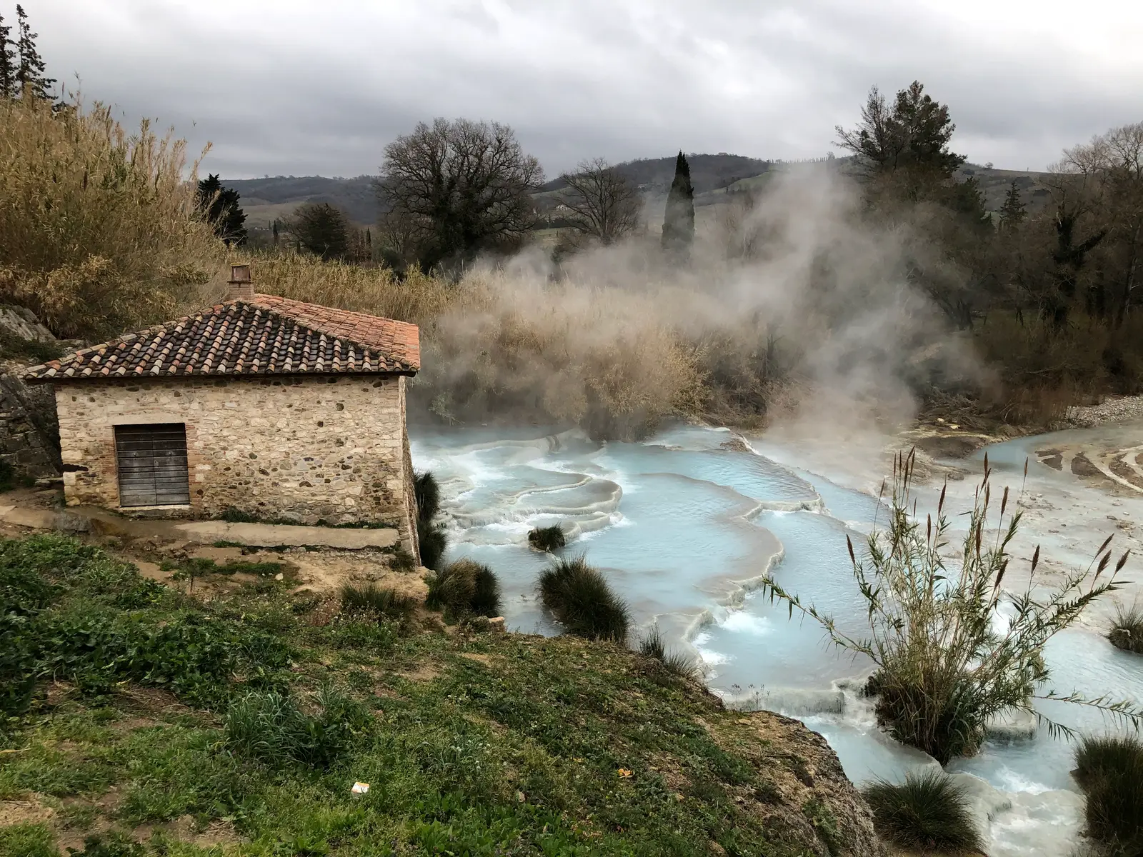 Vasques blanches des Cascate del Mulino, remplies d'une eau thermale bleu pâle et fumante, étagées en contrebas du vieux moulin de pierre, dans les collines de Saturnia.